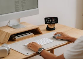 A clean and modern desk setup featuring a computer, clock, and accessories in a home office.
